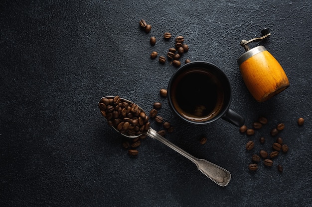 Grains de café, café et cuillère sur une surface sombre