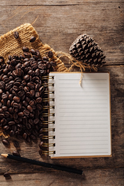 grains de café avec carnet de notes sur fond en bois