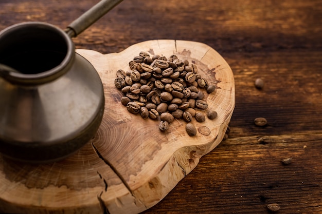 Grains de café et cezve sur un fond en bois.