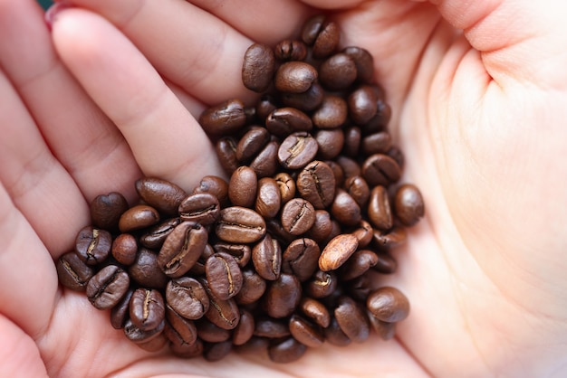 Grains de café couchés dans les mains en forme de coeur gros plan