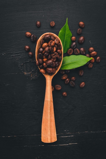 Les grains de café sur une cuillère se trouvent sur un fond en bois Vue de dessus Espace de copie