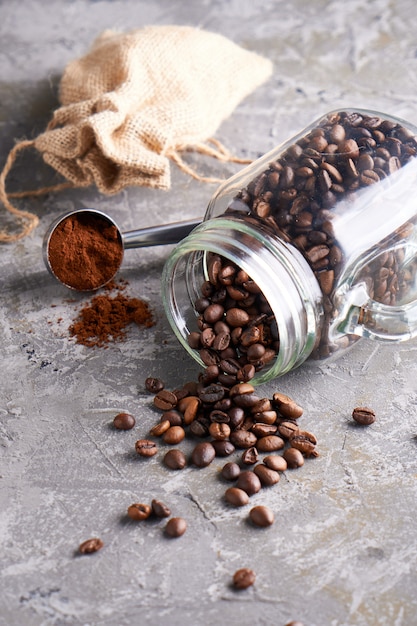 Grains de café dans un bocal en verre sur une table grise Copyspace Vertical