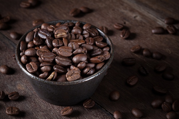 Grains de café dans un bol brun sur la table en bois brun.