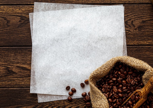 Grains de café dans l'espace de copie de papier blanc sac sur fond de bois