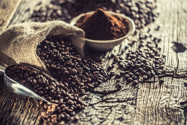 Grains de café dans un sac de jute sur une vieille table en bois.