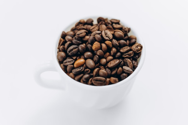 Grains de café dans une tasse blanche sur fond blanc