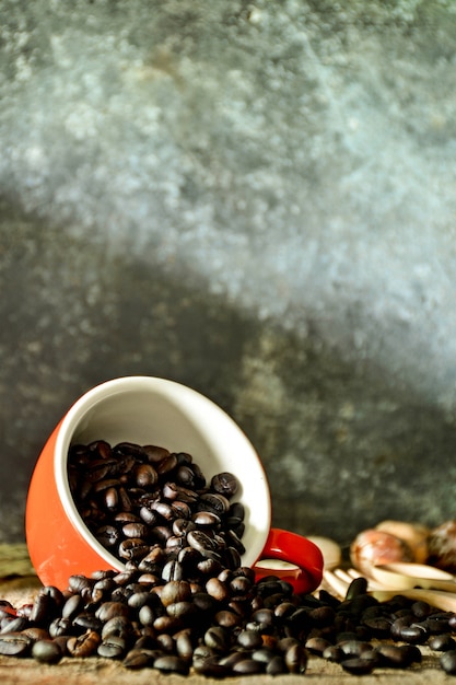 Grains de café dans une tasse en céramique rouge sur le vieux bureau en bois dans la salle de cuisine