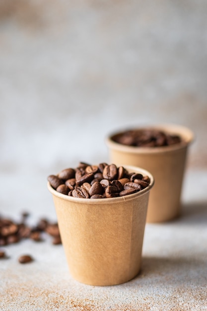Grains de café dans une tasse en papier grains torréfiés frais servant de l'arabica ou du robusta