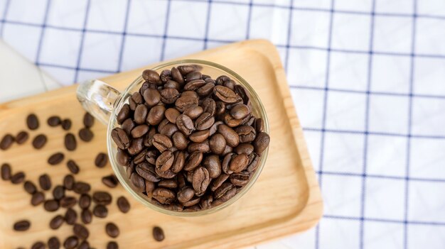 Grains de café dans une tasse sur une table en bois.