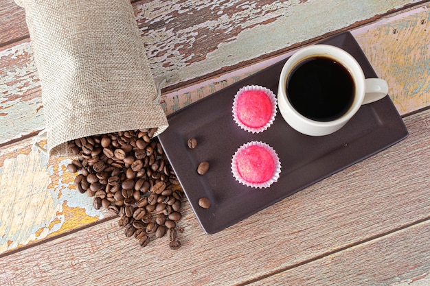 Photo grains de café debout à côté de brigadeiros bicho de pe et une tasse de café (vue de dessus).