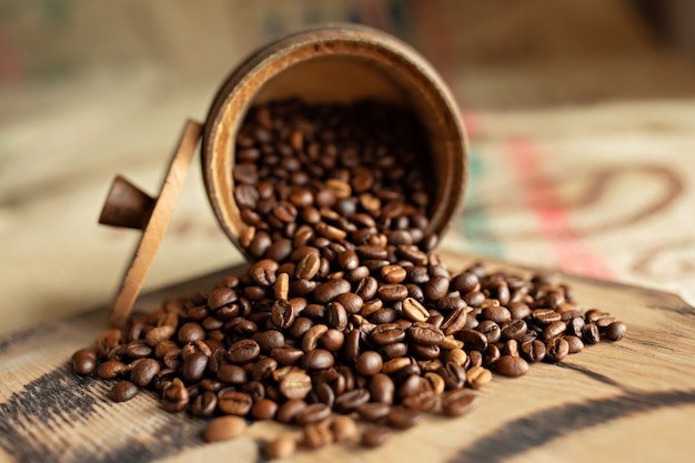 Grains de café épars sur une planche de bois. Fermer