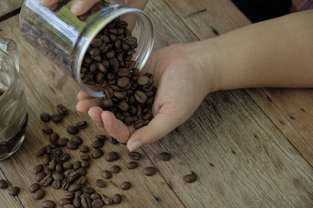 Grains de café étant versé d&#39;une bouteille dans la paume.