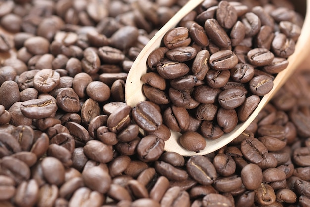 Grains de café frais et cuillère sur table.