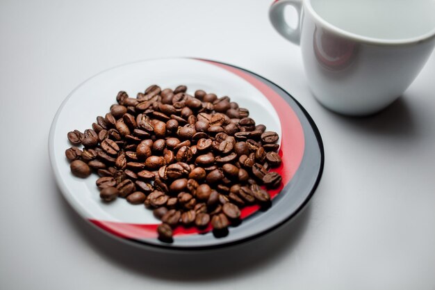 Grains de café frits et tasse blanche isolé sur fond blanc