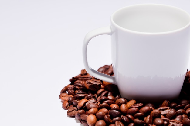 Grains de café isolés avec tasse en céramique, blanc.