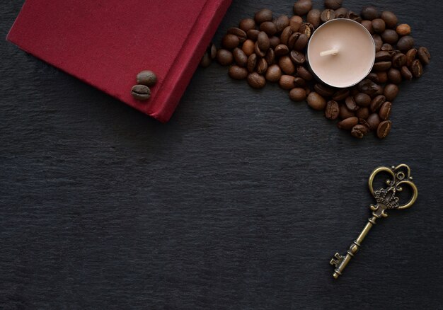 Grains De Café Et Livre Rouge Et Bougie Sur Table Noire