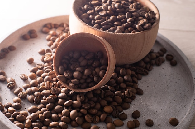 Grains de café noir dans une tasse en bois. Image symbolique. Fond en bois rustique. Fermer. Copiez l'espace.