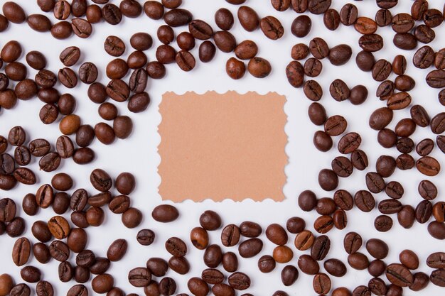 Grains de café placés autour de papier vierge pour copyspace