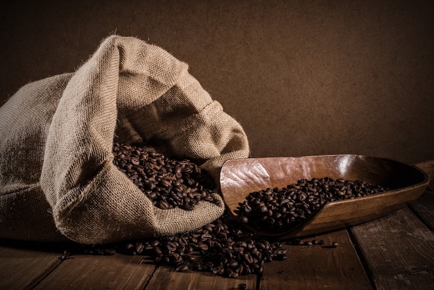 Grains de café avec sac de jute et écope sur fond grunge