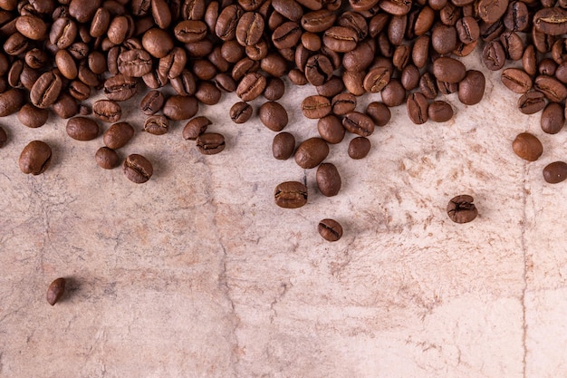 Les grains de café sont éparpillés sur un gros plan de fond beige