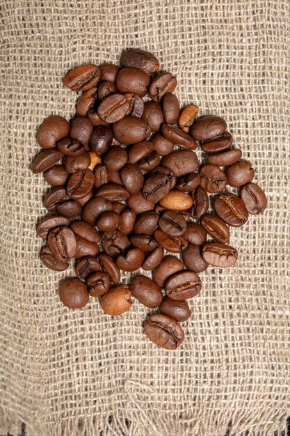 Les grains de café sont éparpillés sur la toile de jute.