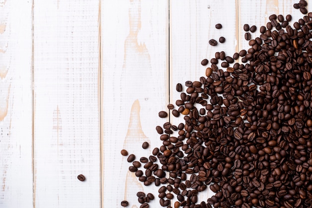 Grains de café sur une table en bois blanc