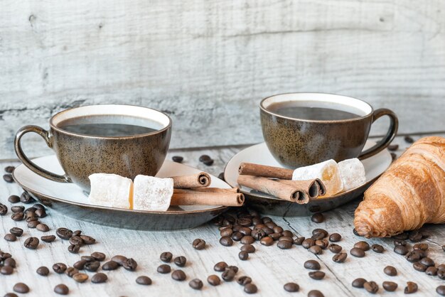 Grains de café sur table en bois avec des bonbons et des croissants