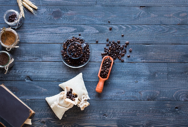 Grains de café et tasse de café avec d'autres composants sur différents fond en bois.