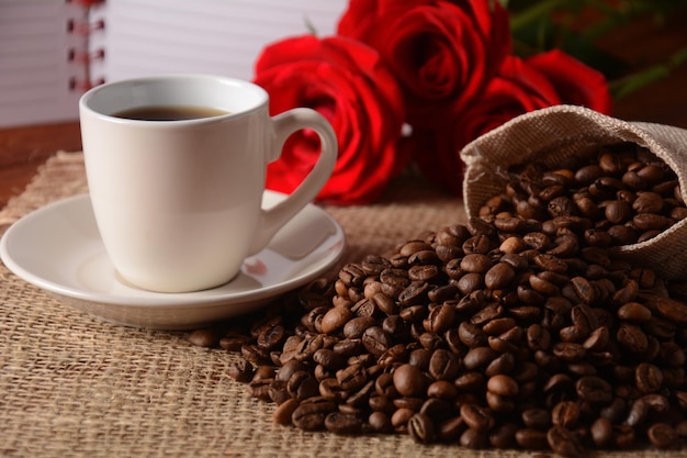 Grains de café et une tasse de café et de fleurs roses