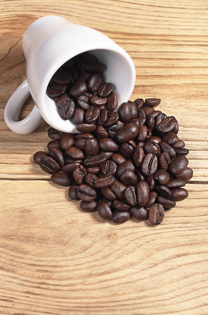 Grains de café en tasse et dispersés sur une vieille table en bois