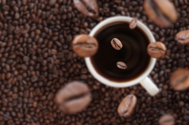 Les grains de café tombent dans une tasse de café Boisson énergisante caféine Mise au point sélective