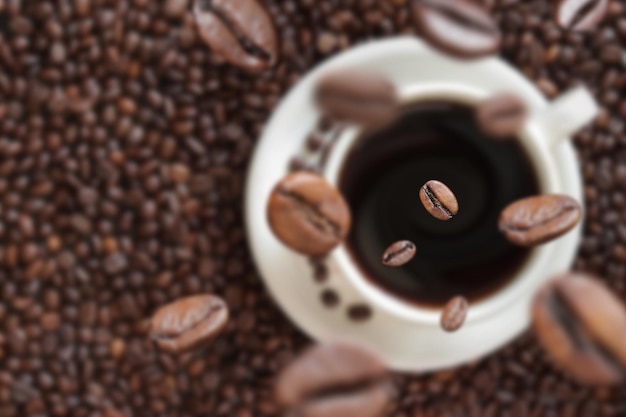 Les grains de café tombent dans une tasse de café Boisson énergisante caféine Mise au point sélective