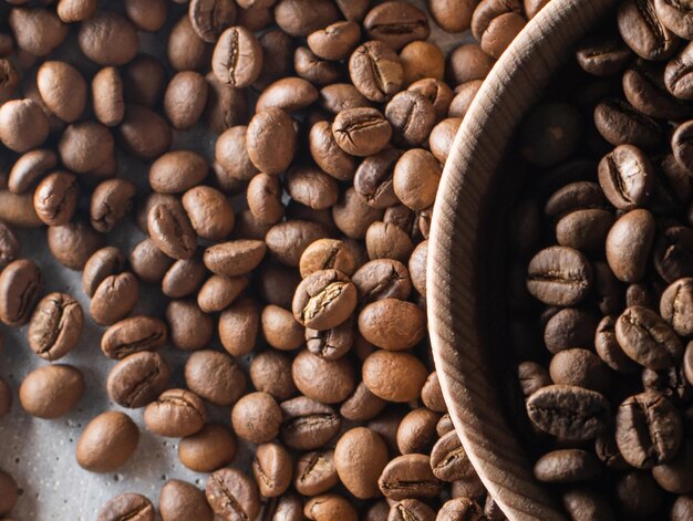 Grains de café torréfiés bruns tombant sur pile. Représenter le petit-déjeuner, l'énergie, la fraîcheur ou le bon arôme, Voler sur fond sombre avec espace de copie, gros plan.