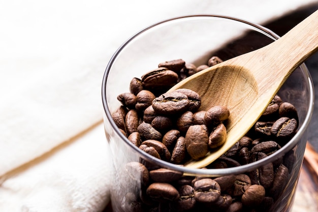 Grains de café torréfiés avec une cuillère en bois agrandi l'espace d'image pour le texte