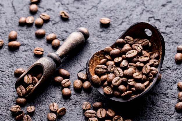 Grains de café torréfiés avec une cuillère en bois agrandi l'espace d'image pour le texte