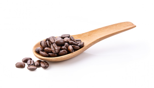 Grains de café torréfiés en cuillère de bois isolé sur fond blanc