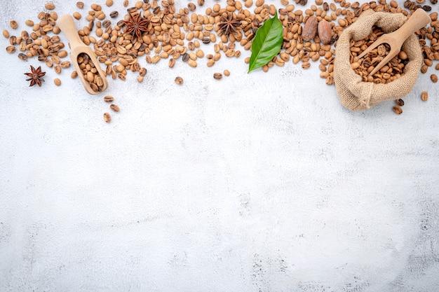 Grains de café torréfiés avec des cuillères sur du béton blanc.