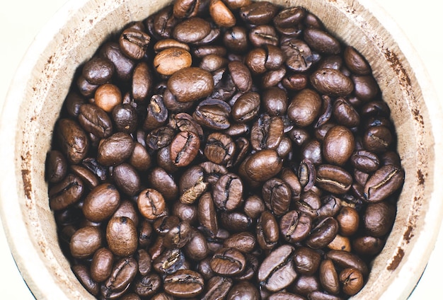 Grains de café torréfiés dans le pot en bois Photo macro en gros plan