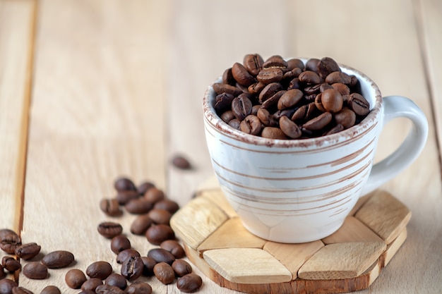 Grains de café torréfiés dans une tasse en céramique image symbolique copy space