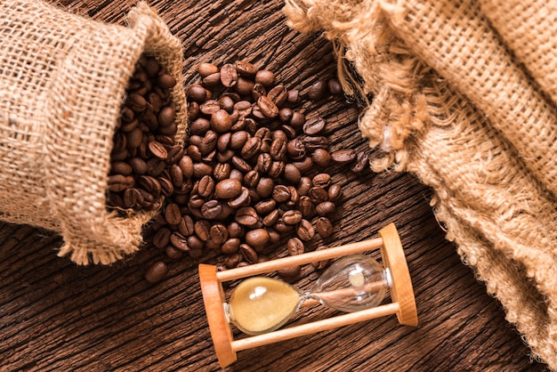 grains de café torréfiés éclaboussent du sac sur la table en bois