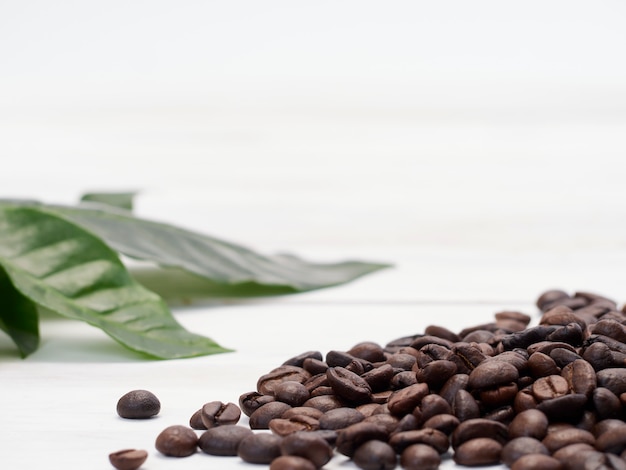 Grains de café torréfiés avec des feuilles de café.