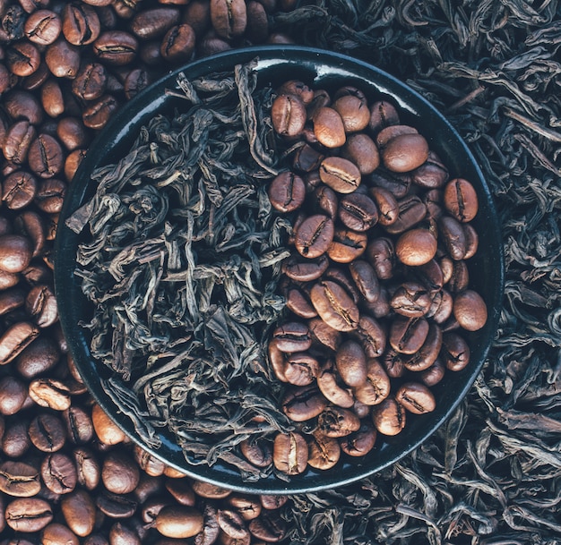 Grains de café torréfiés et feuilles sèches de thé noir, gros plan vue de dessus