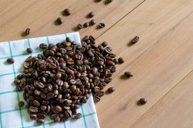 Grains de café torréfiés sur fond de bois.