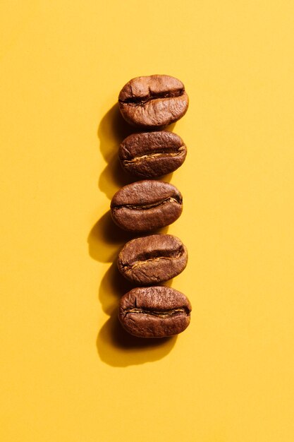 Grains de café torréfiés sur fond jaune