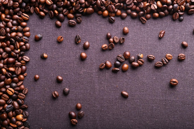 Grains de café torréfiés sur un fond textile gris