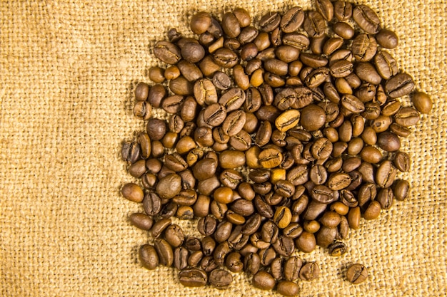 Grains de café torréfiés sur fond tissé sac