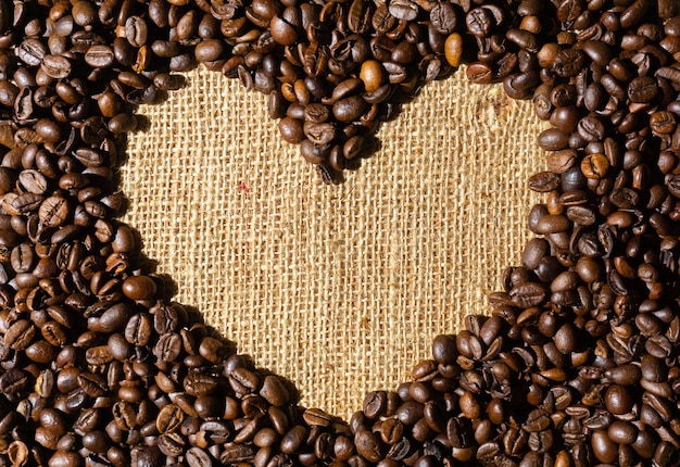 Grains de café torréfiés en forme de cadre en forme de cœur. Sur sac de chanvre brun.