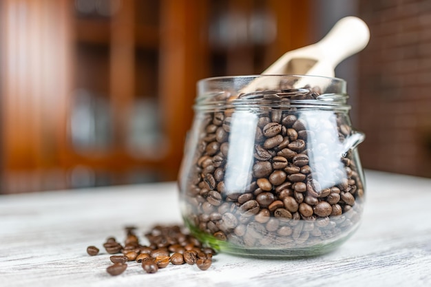 Grains de café torréfiés naturellement dans un bocal en verre antique et cuillère en bois pour les ramasser