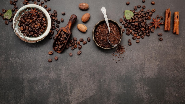 Grains de café torréfiés avec de la poudre de café et des ingrédients savoureux pour préparer un café savoureux sur fond de pierre sombre