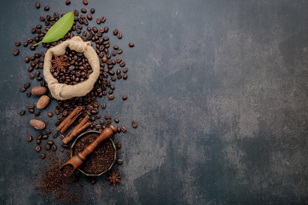 Grains de café torréfiés avec de la poudre de café et des ingrédients savoureux pour préparer un café savoureux sur une pierre sombre.